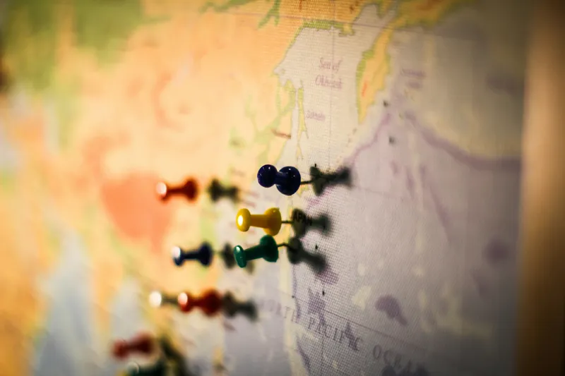 World map with colorful push pins marking top destination countries for Americans after renouncing US citizenship